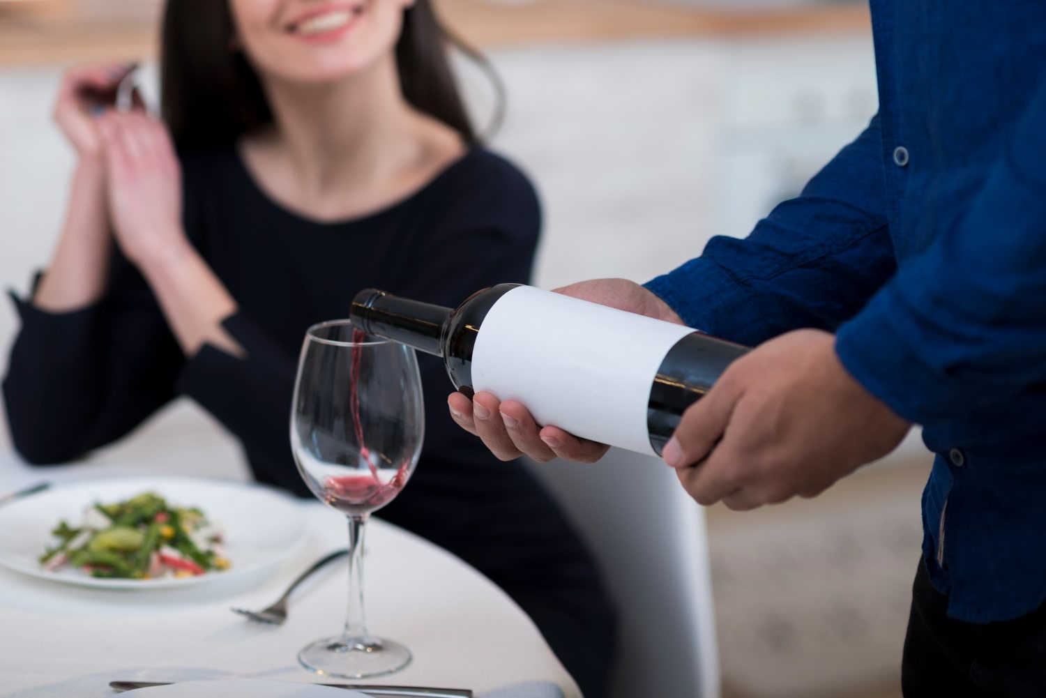 The waiter pours the wine